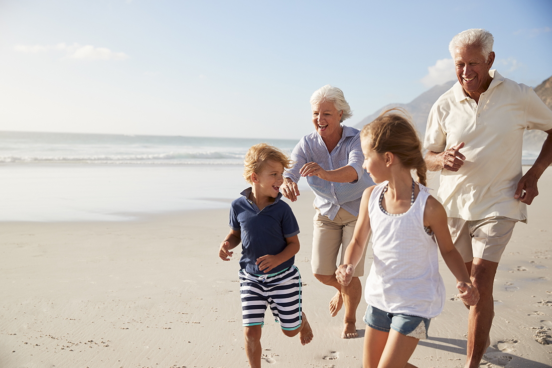 Grandparents playing with their grandchildren on the beach